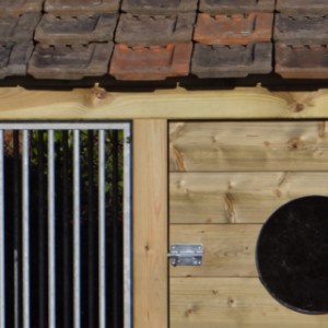 Verduurzaamd hout, gegalvaniseerd traliewerk, dakpannen en plexiglas.